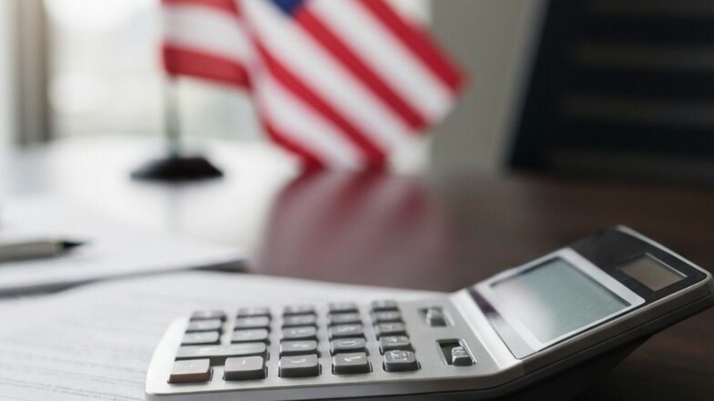 Tax documents and calculator on desk, American flag in background, professional setting